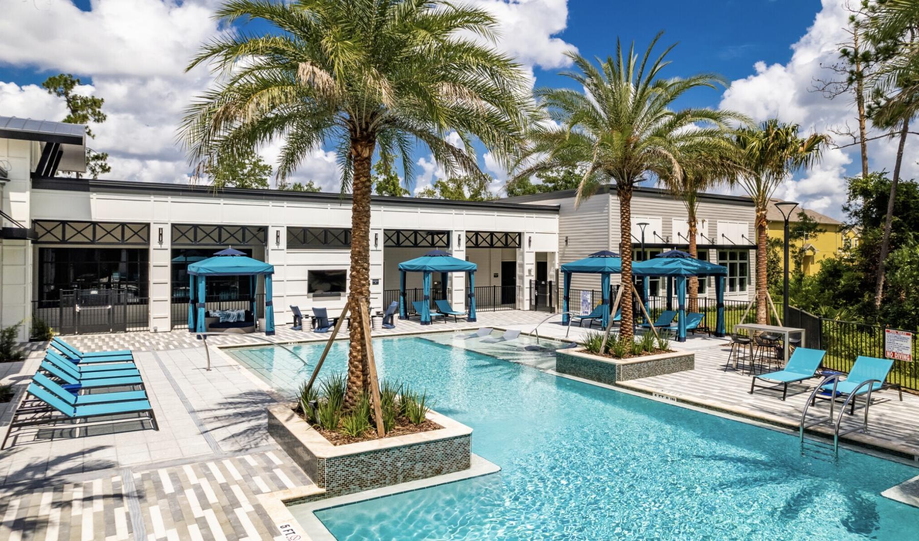 a pool with palm trees and a building in the background