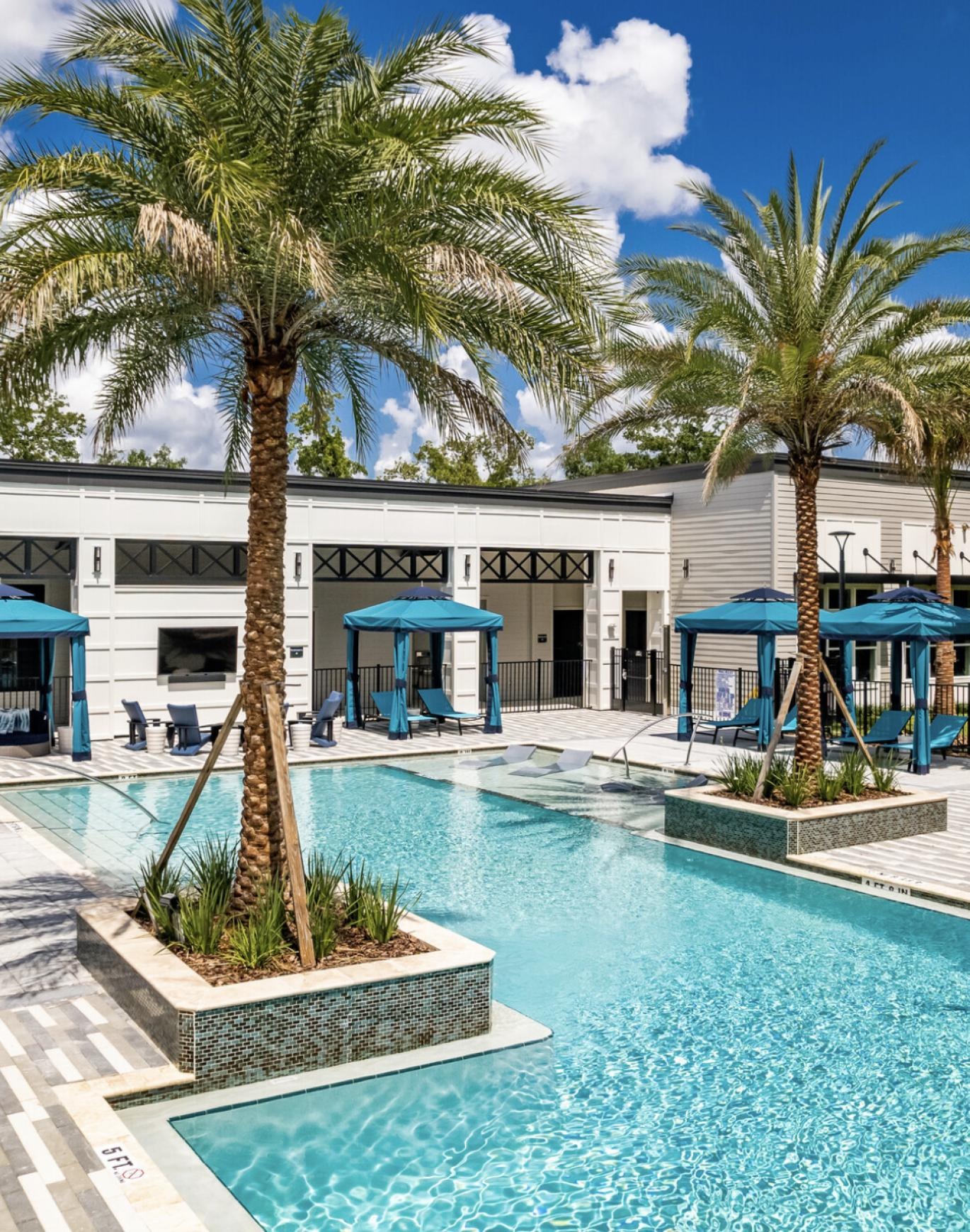 a pool with palm trees and a building in the background
